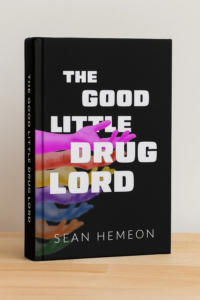 A black book titled The Good Little Drug Lord by Sean Hemeon, featuring white bold text and overlapping colorful hand silhouettes on the cover, stands upright on a light wooden surface. This striking design perfectly complements Sean Hemeon’s compelling storytelling within.